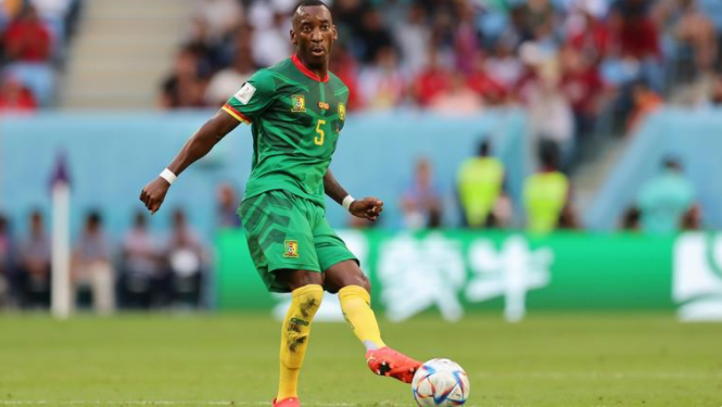 喀麦隆国家队球员在世界杯赛场上穿着带国旗的球鞋踢球