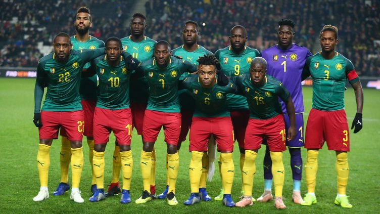 喀麦隆国家队球员在世界杯赛场上穿着带国旗的球鞋踢球